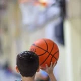 Niño sosteniendo una pelota de básquet en cancha